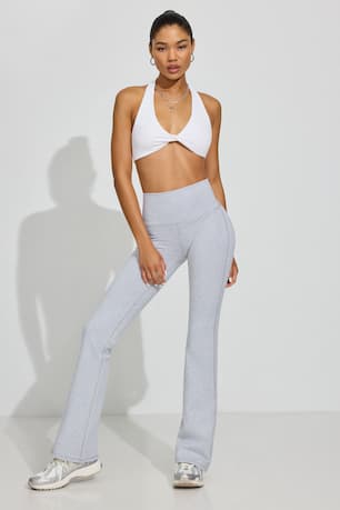 Model wears a white halter bra top and grey sweats. 